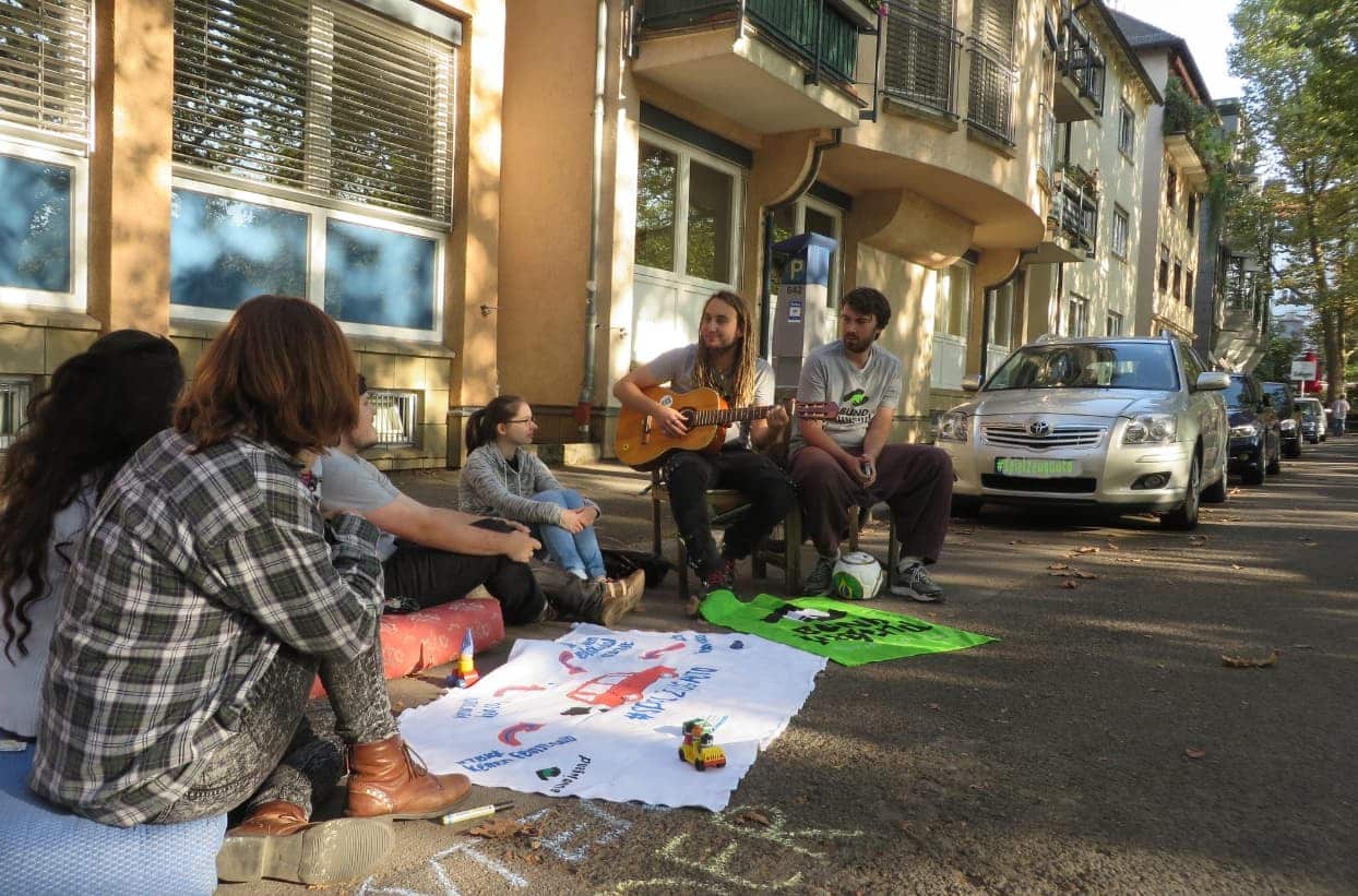 Gruppe sitzt auf Straße und spielt Gitarre