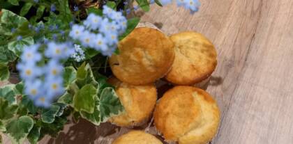 Muffins neben blühenden Pflanzen auf Holztisch
