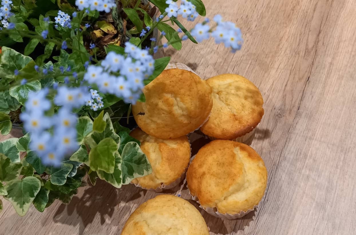 Zitronenmuffins und Blümchen auf Holztisch