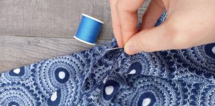 Hand näht blau gemusterten Stoff mit Faden