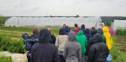 Personengruppe vor einem Gewächshaus im Regen