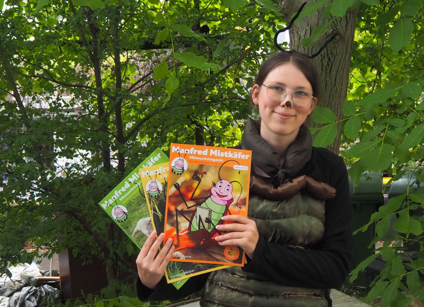Manfred Mistkäfer hält Manfred Mistkäfer Magazine 2024 in den Händen.