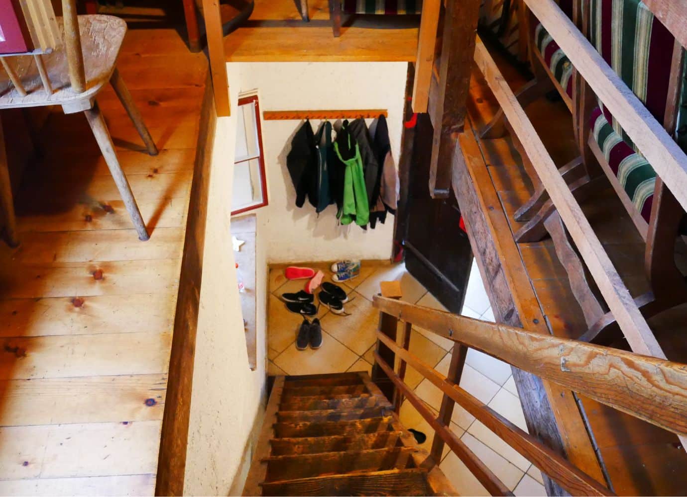 Holztreppe zu Eingang mit Schuhen und Jacken.