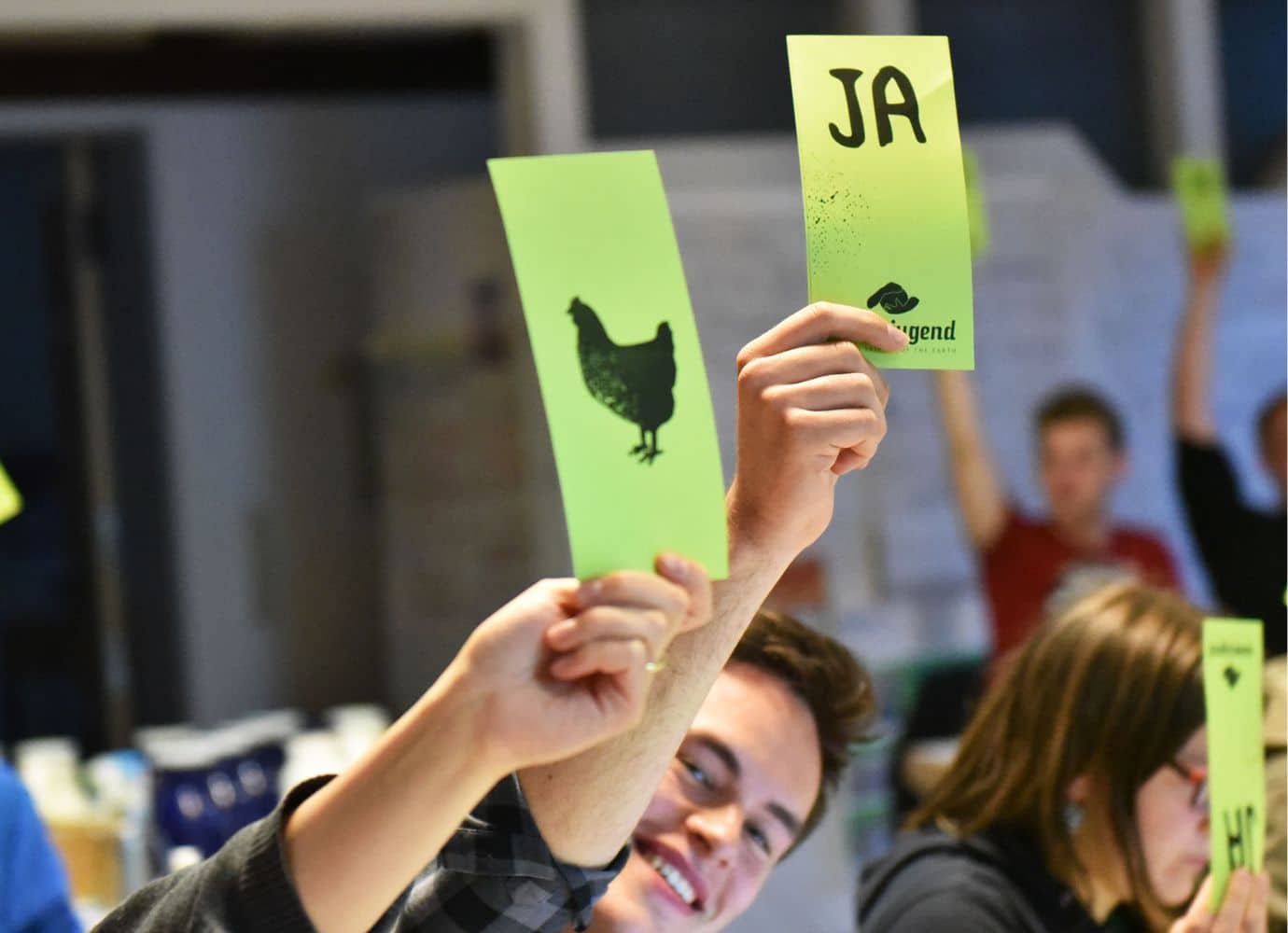 Menschen heben grüne Karten bei einer Abstimmung.