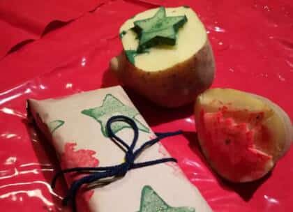 Kartoffelstempel und Geschenk auf roter Tischdecke