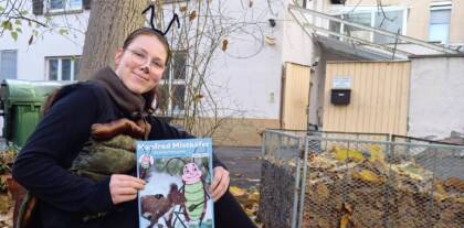 Person vor Baum mit Magazin in der Hand.
