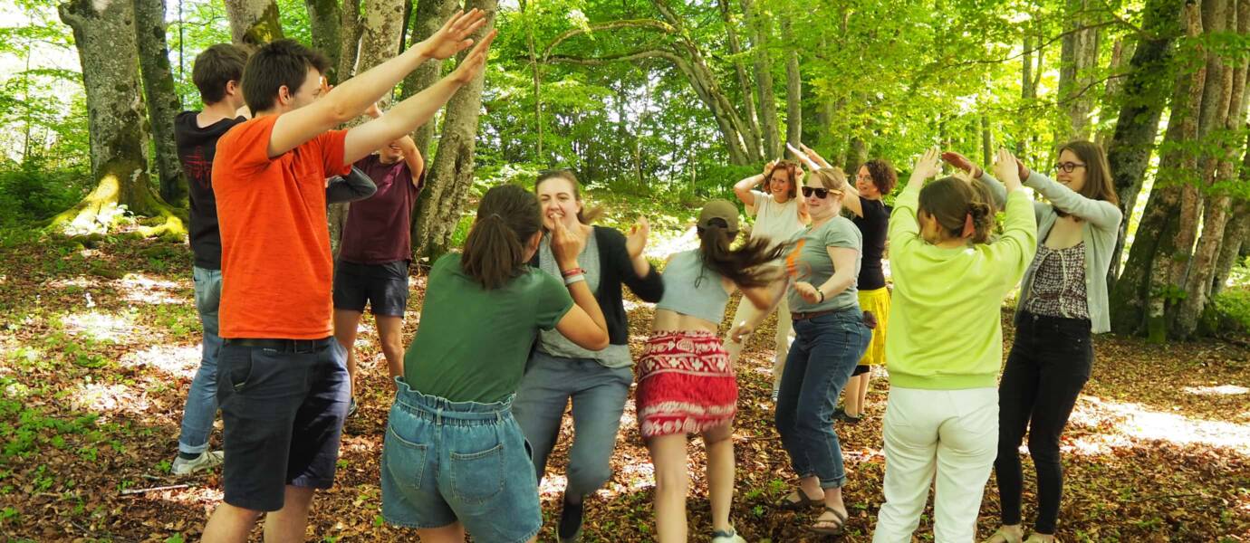 Gruppe tanzt fröhlich im Wald.