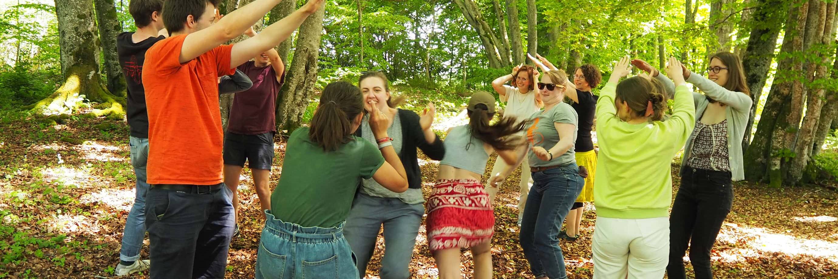 Gruppe tanzt fröhlich im Wald.
