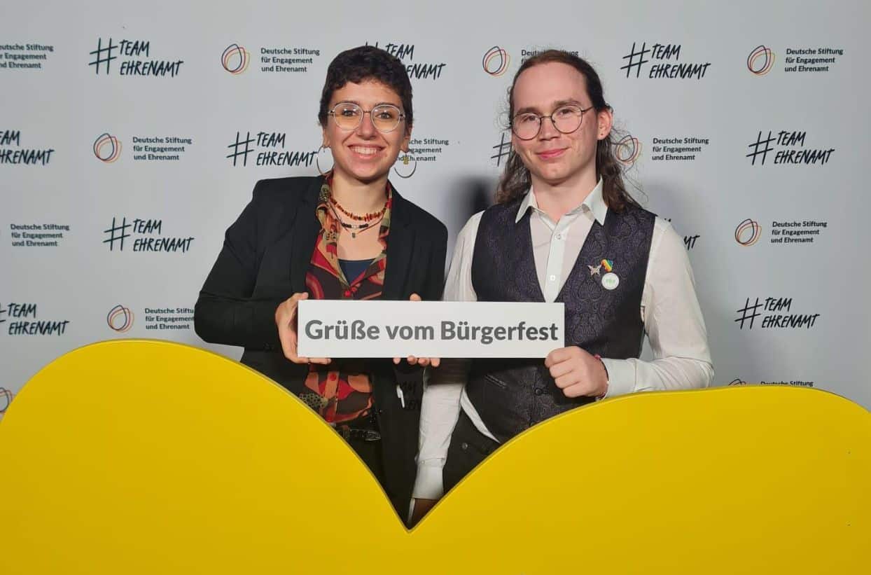 Zwei Personen halten Schild beim Bürgerfest hoch.