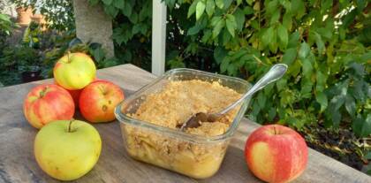 Apfelcrumble mit frischen Äpfeln auf Holztisch
