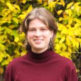 Lächelnde Person vor gelbem Laub